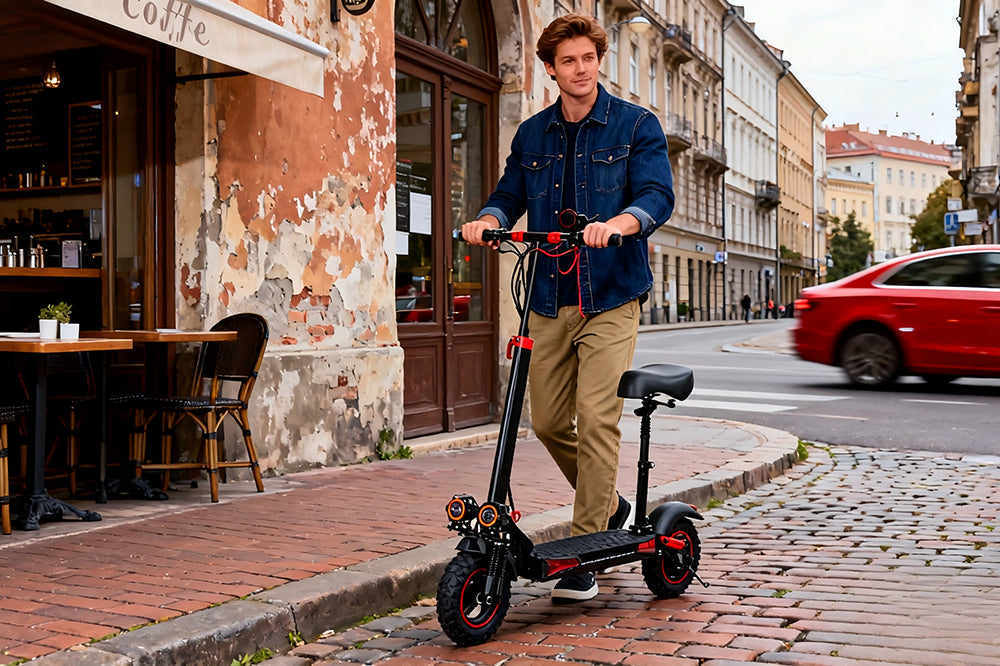 Freeboy J11 Max foldable city electric scooter with seat, being ridden on cobblestone street outside a European café